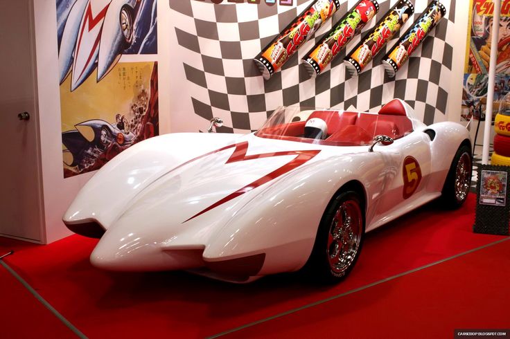 a white sports car is on display in a room with red carpet and checkered walls