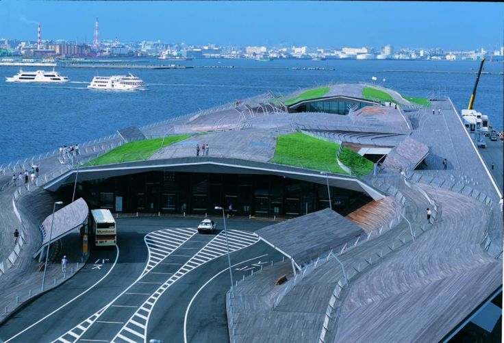 an aerial view of a green roof on a building by the water with boats in the background