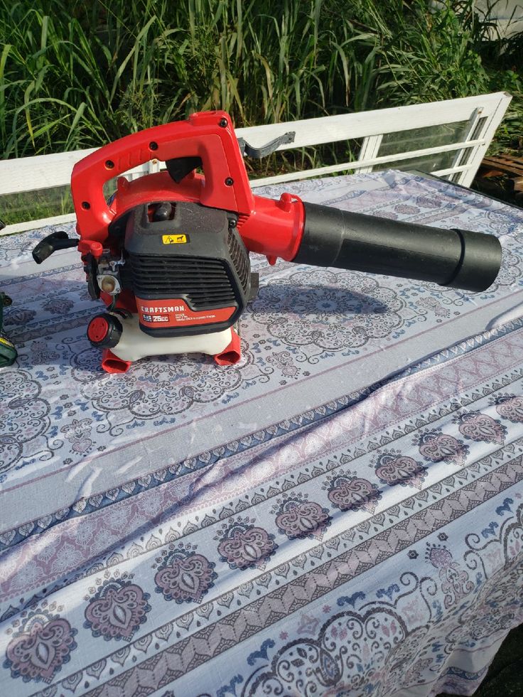 a red and black blow dryer sitting on top of a tablecloth covered table