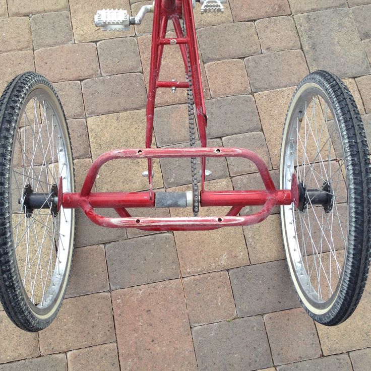 a red tricycle parked on top of a brick sidewalk