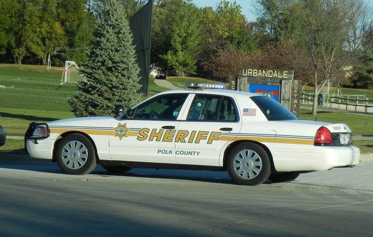 a sheriff car parked on the side of the road in front of a park area