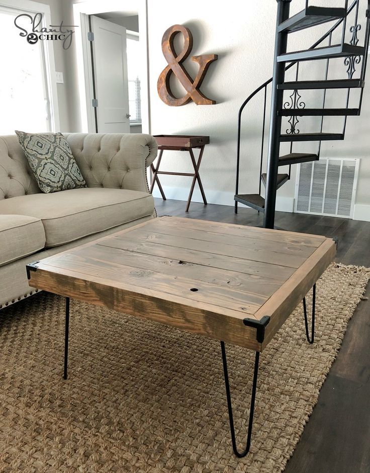 a living room with a couch, coffee table and spiral stair case in the background