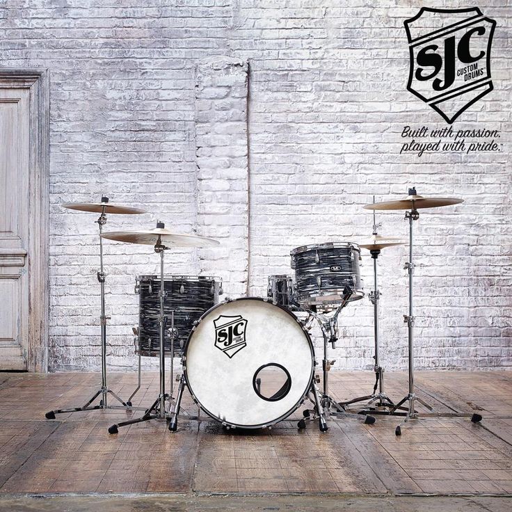 a drum set sitting on top of a hard wood floor next to a brick wall