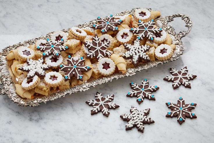 a tray filled with cookies and snowflakes on top of a marble countertop