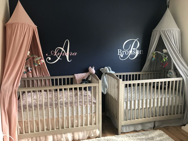 two baby cribs in a room with blue walls and pink drapes on the wall