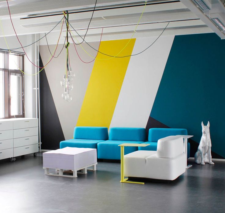 a living room filled with furniture next to a wall painted in different colors and shapes