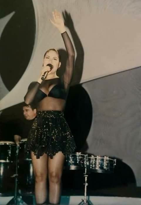 a woman standing on top of a stage with her arms in the air and holding a microphone