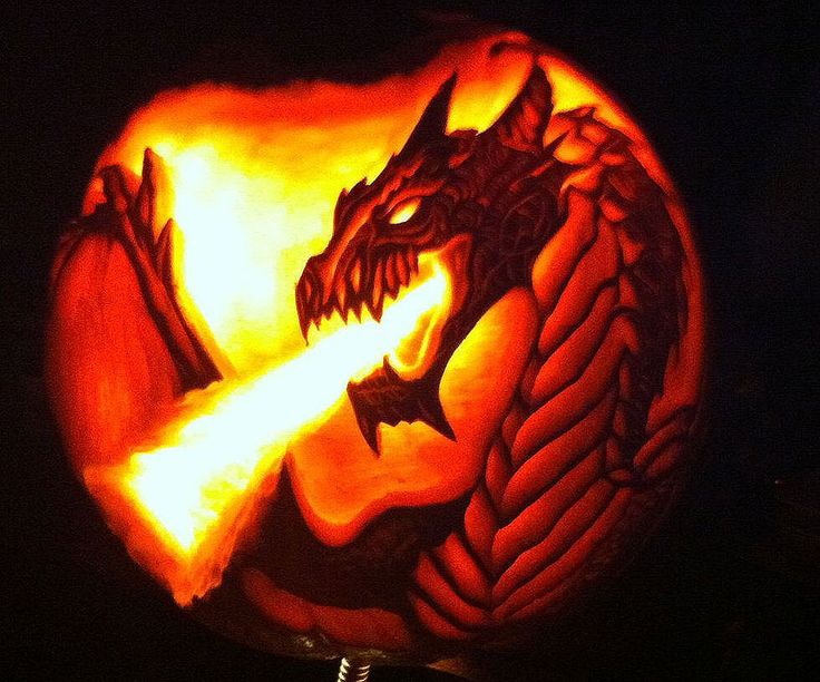 a carved pumpkin with an image of a dragon on it's face and fire coming out of its mouth