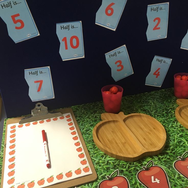 an apple themed classroom display with numbers and apples on the floor, along with two wooden trays filled with apples