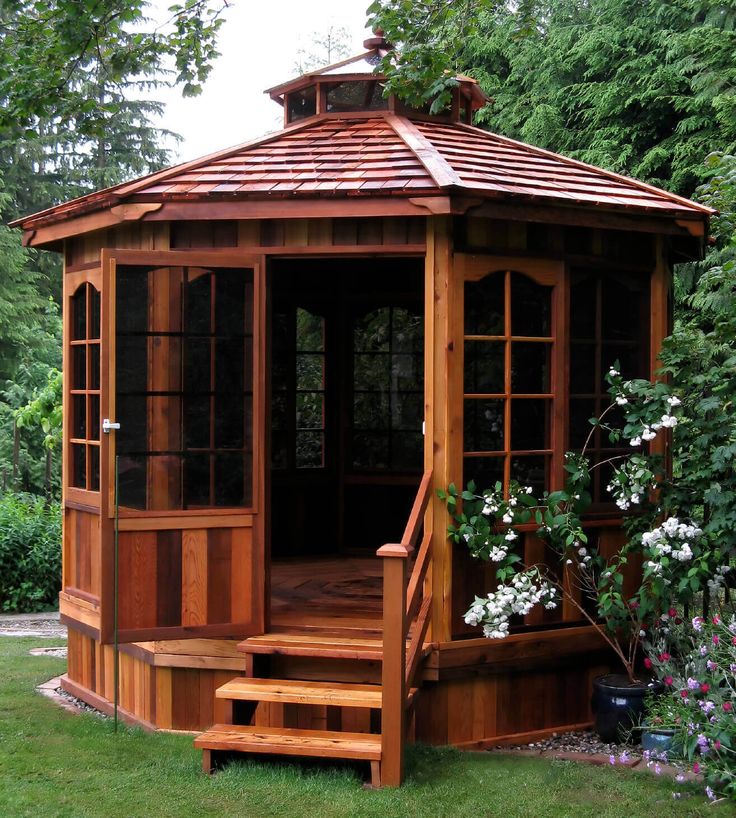 a wooden gazebo sitting on top of a lush green field