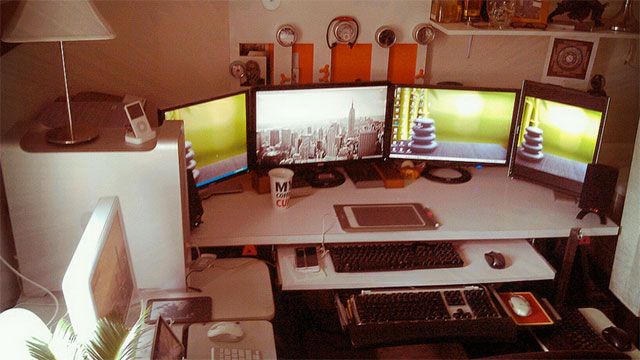 three computer monitors sitting on top of a desk next to a keyboard and monitor screen