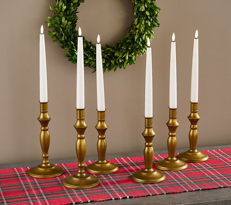 a set of five candles sitting on top of a table next to a christmas wreath