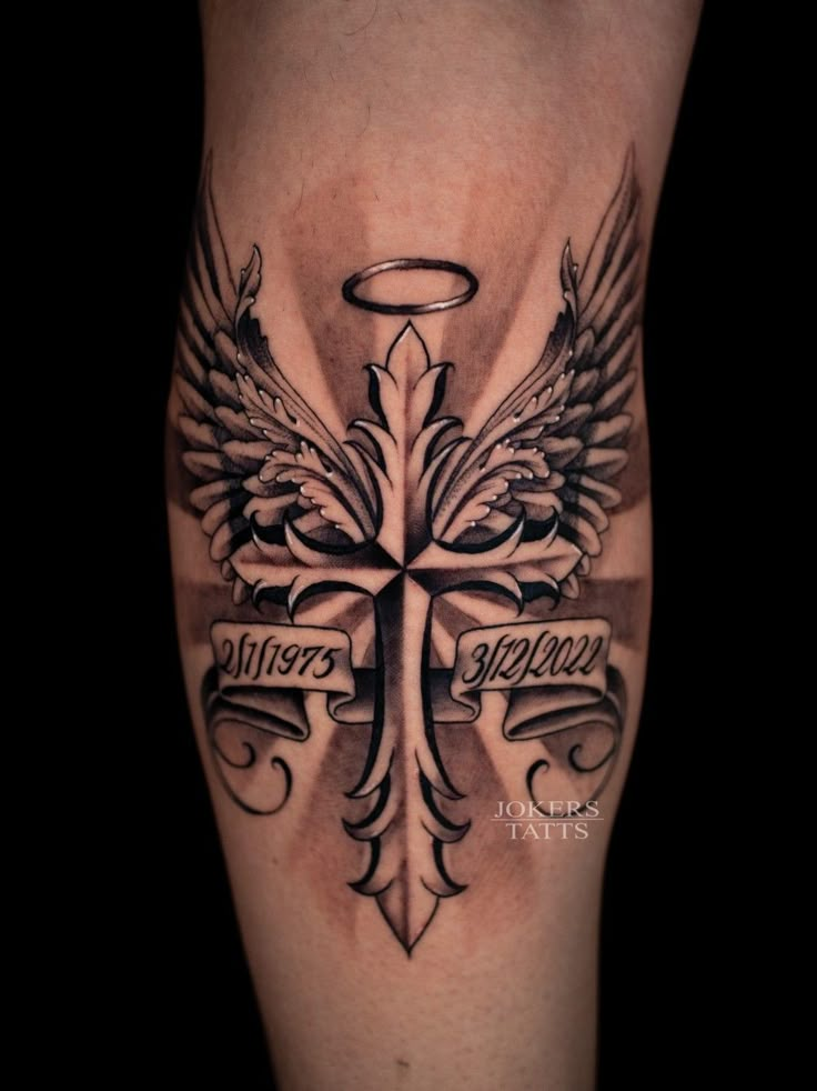 a cross with wings and an angel tattoo on the leg is seen in this image