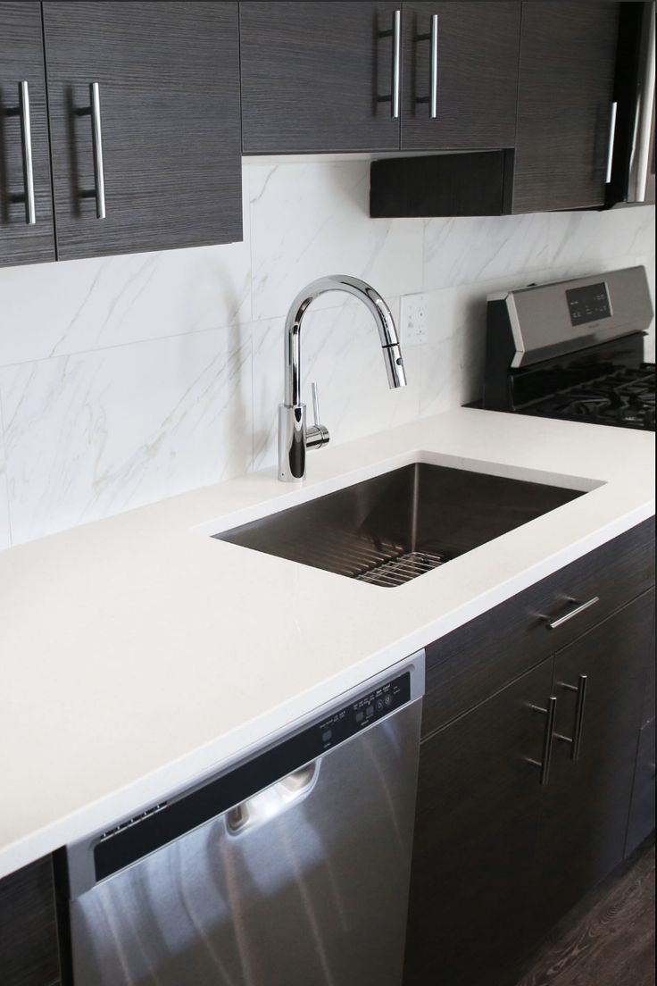 a modern kitchen with stainless steel appliances and marble counter tops, including a dishwasher