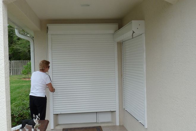 a woman standing in front of a white door with two dogs on leashes next to it