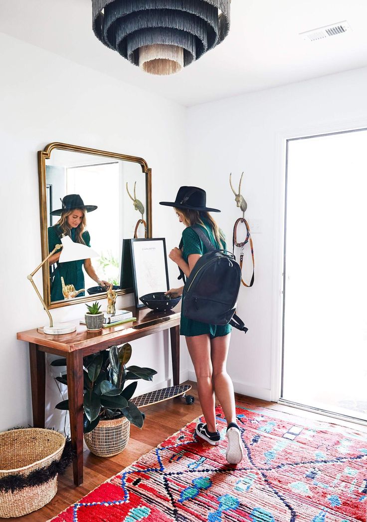 two women standing in front of a mirror and looking at their own pictures on the wall