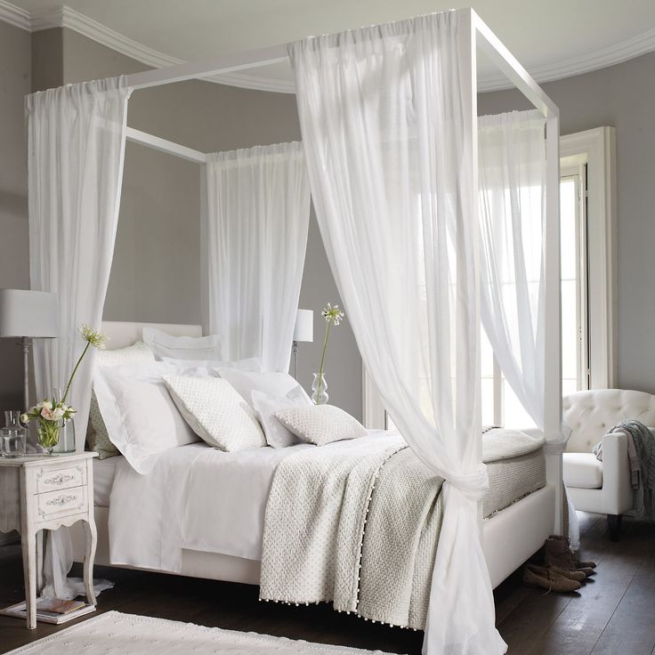 a white bed sitting in a bedroom next to a window