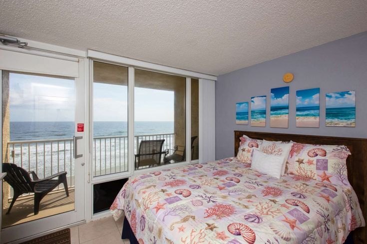 a bed sitting in a bedroom next to a sliding glass door with an ocean view