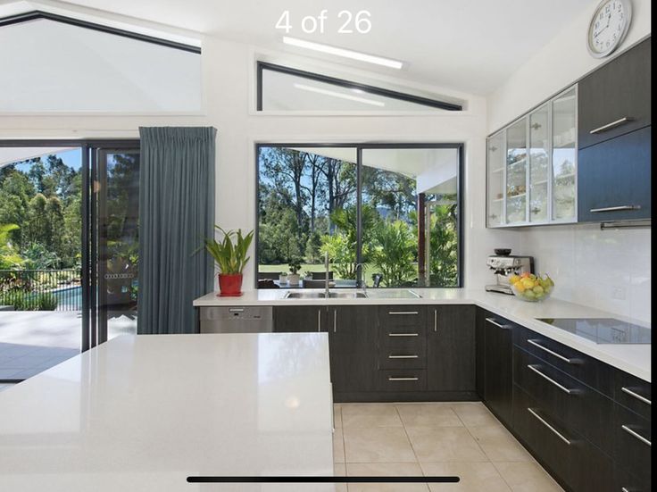 a large kitchen with lots of counter space and windows overlooking the trees in the back yard