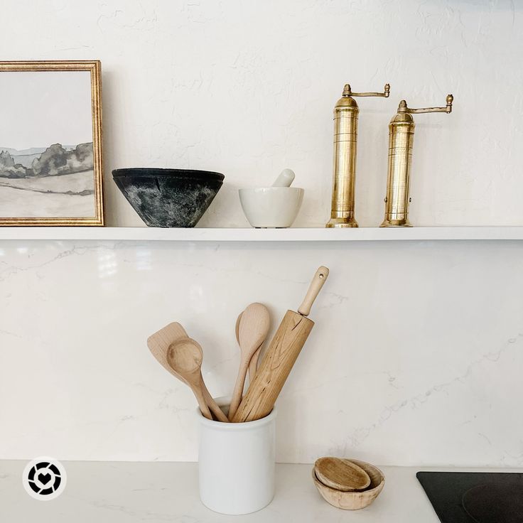 kitchen utensils and wooden spoons in a white cup on a counter top