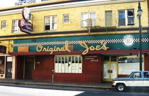 an old fashioned storefront on the corner of a street with a truck parked in front