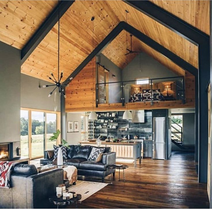 a living room filled with furniture and a fire place in the middle of a wooden floor