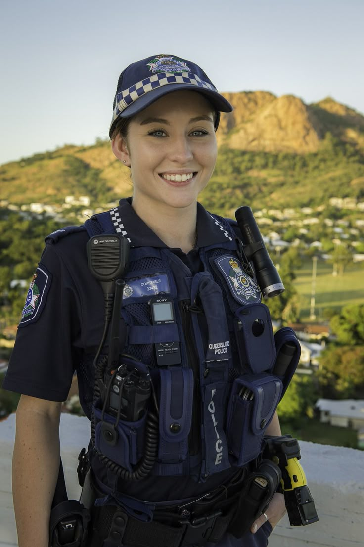 a woman police officer standing in front of a mountain with her hand on her hip