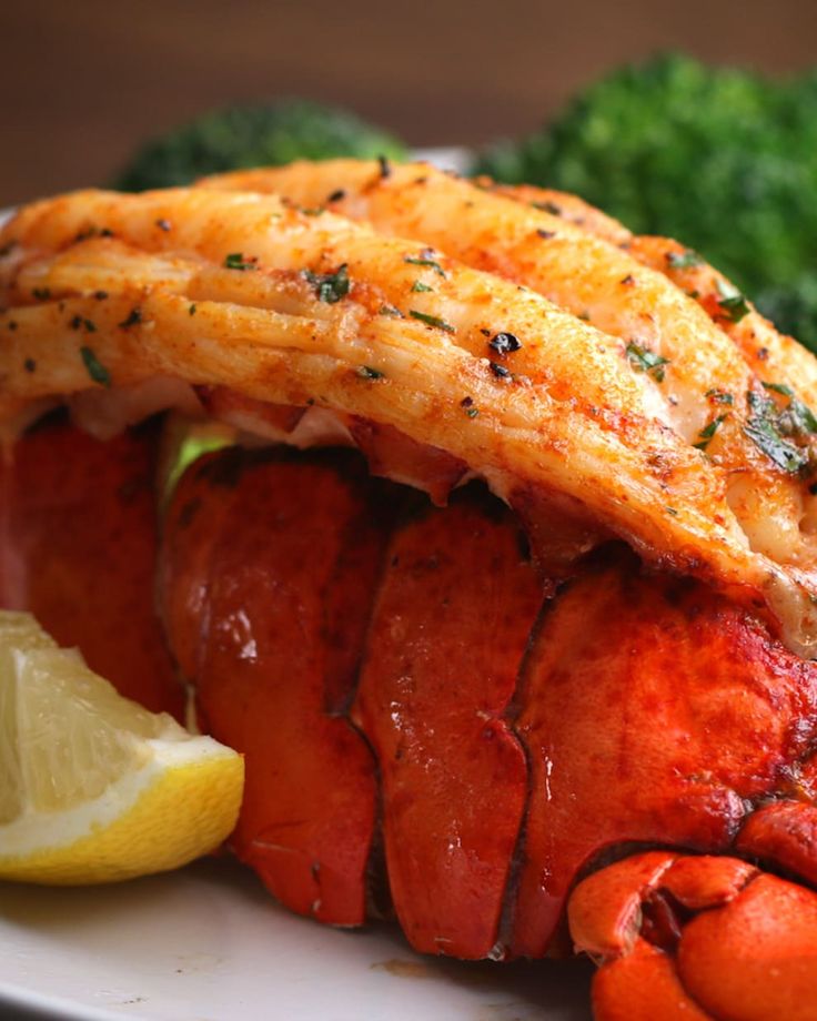 lobster, broccoli and lemon on a white plate with some sort of garnish