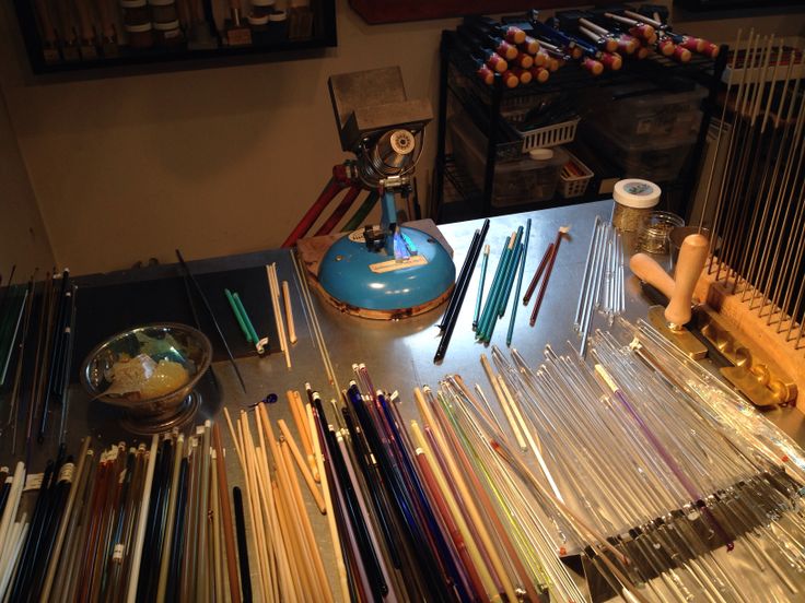 an assortment of knitting needles on a table in a room with many other items around it