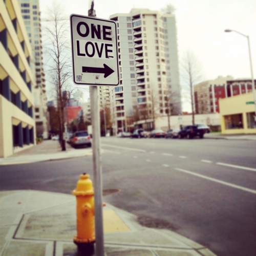 a one love street sign next to a yellow fire hydrant