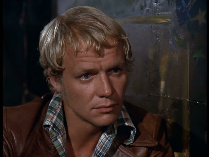 a man with blonde hair wearing a brown leather jacket