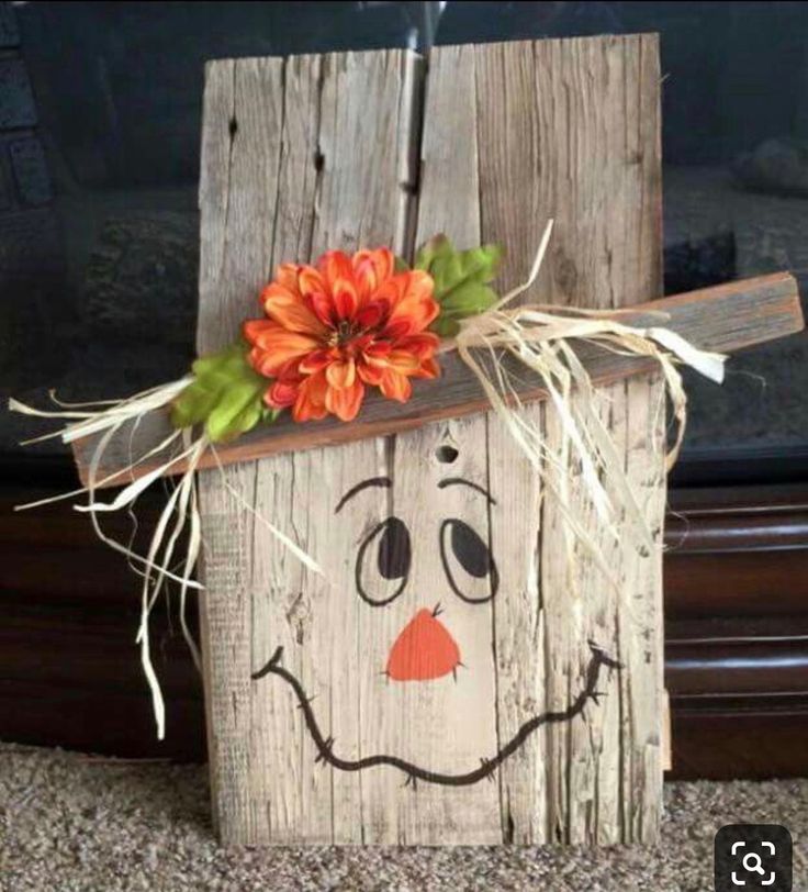 a wooden block with a face painted on it and a flower sticking out of the top