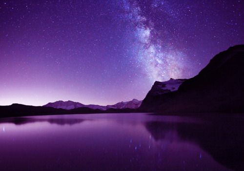 the night sky is filled with stars and bright purple hues as seen from a mountain lake