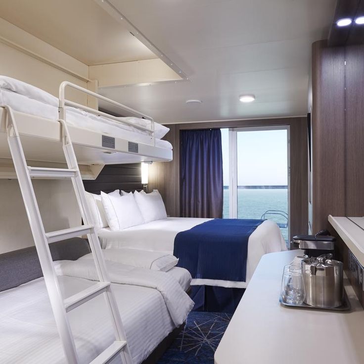 a bedroom with bunk beds and a desk in front of a window that looks out to the ocean