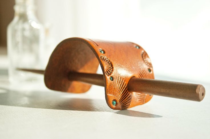 a close up of a wooden object on a table with a bottle in the background