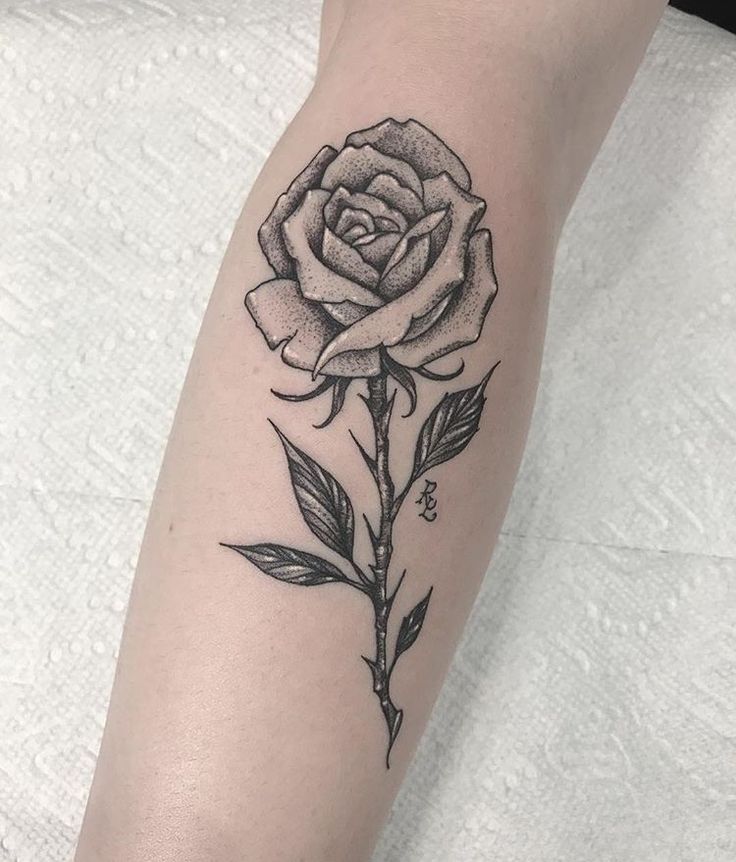 a black and white rose tattoo on the arm