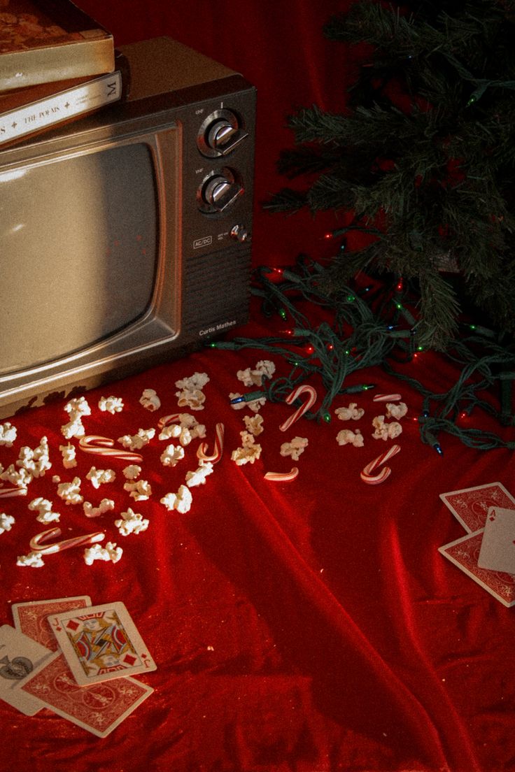 an old tv sitting on top of a red table cloth next to a christmas tree