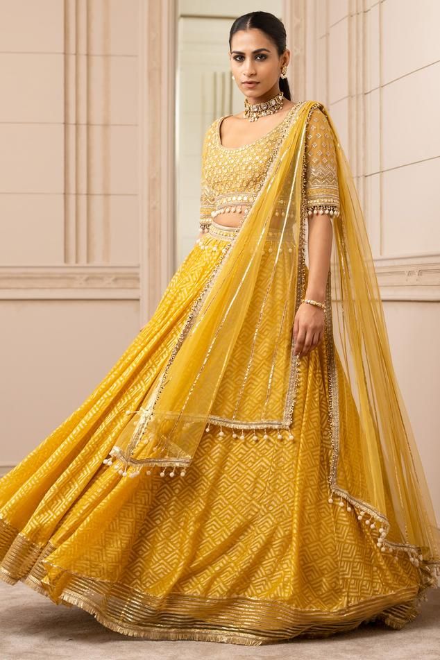 Yellow kalidar sheer brocade lehenga with a pearl-laced waistband and gota border. Paired with a mirror-embroidered round-neck blouse with pearl detailing on the hem along with delicate wings with gota trims and fringe embellished dupatta.
Component: 3
Pattern: Embroidered
Type Of Work: Geometric
Neckline: Round
Sleeve Type: Elbow Sleeves
Fabric: Silk organza brocade
Color: Yellow
Other Details: 
Back tie-up
Embroidered waistband
Tassel detail
Striped panel
Occasion: Destination Wedding - Aza Fa Diwali Reception Choli With Sheer Dupatta, Eid Sharara With Pallu For Reception, Yellow Organza Sets With Mirror Work, Diwali Organza Lehenga With Traditional Drape, Choli With Sheer Dupatta For Reception Navratri, Sets With Dupatta For Reception During Navratri, Sheer Dupatta Art Silk Sharara For Reception, Traditional Organza Lehenga With Gota Work, Transitional Organza Lehenga With Cutdana