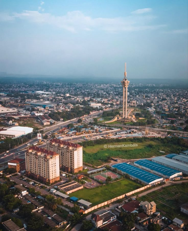 an aerial view of a city with tall buildings and green fields in the foreground