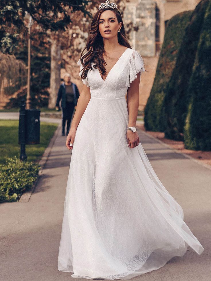 a woman in a white dress is walking down the street with her hand on her hip