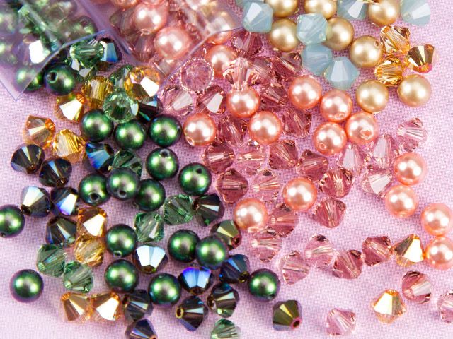 several different colors of beads on a pink surface