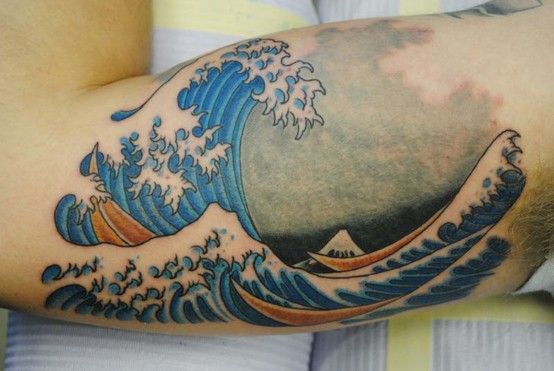 a man with a tattoo on his arm that has an ocean wave coming out of it