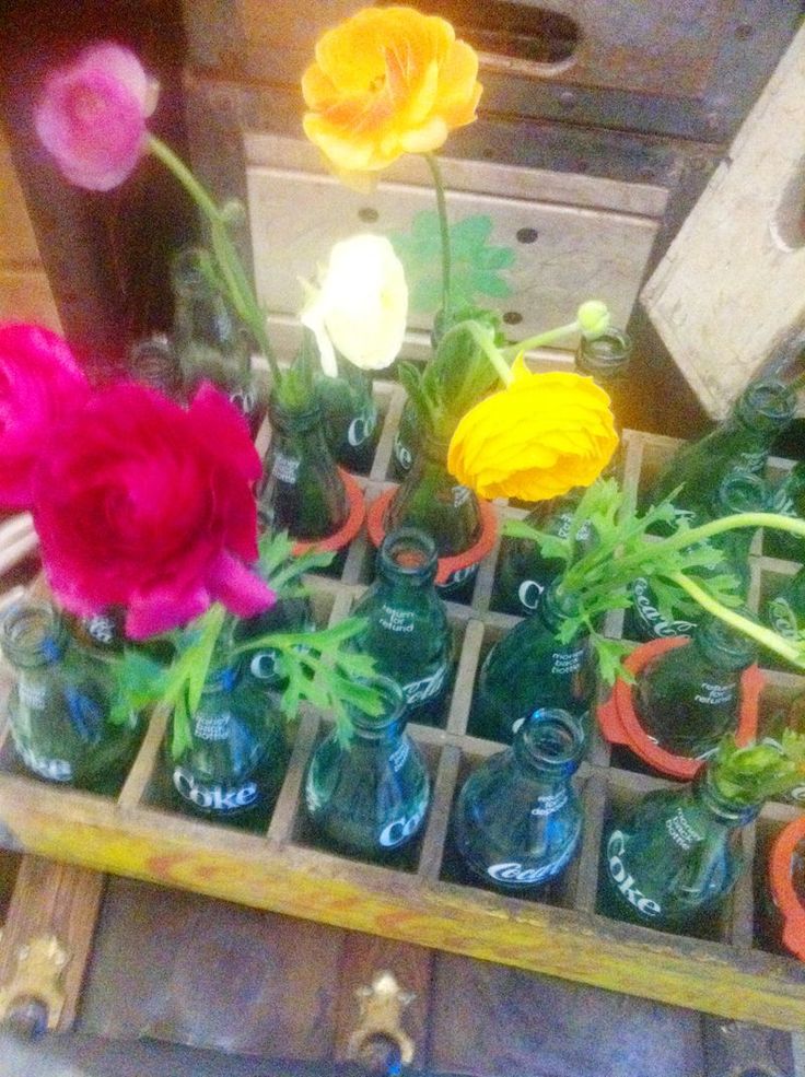 there are many different colored flowers in glass bottles on the table and one is empty