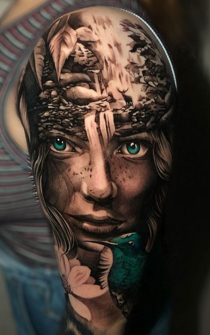 a woman's face with blue eyes and an artistic tattoo design on her arm