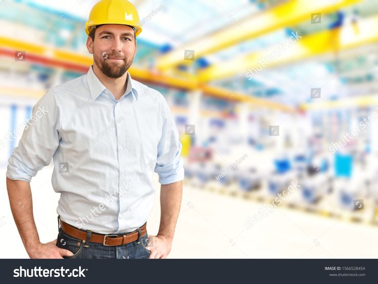 a man wearing a hard hat and standing in front of an empty room with yellow beams