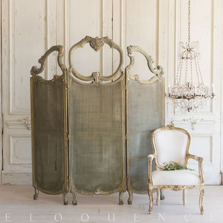 an old fashioned room divider next to a white chair and chandelier hanging from the ceiling