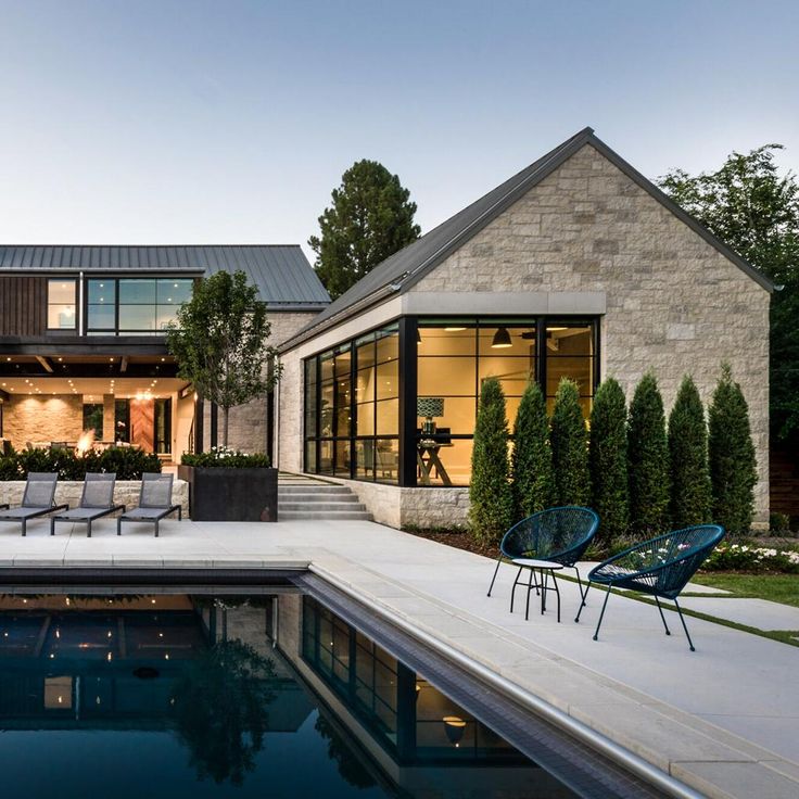 a house with a swimming pool and lounge chairs in front of the house at dusk