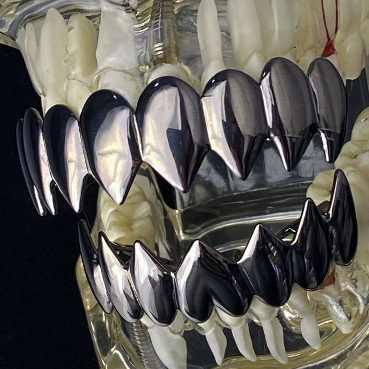 toothbrushes are lined up in a clear glass container with black and white teeth