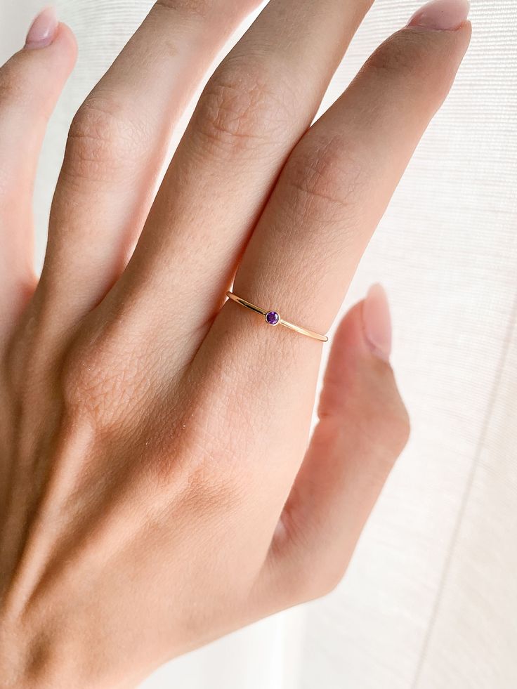 Our February Ring is the perfect gift for anniversary, wedding, bridal proposal, birthday or for a new mama to be! They are great stacking rings as well and look great with any of our other stacking rings. DETAILS: - February birthstone - 14k Gold Fill, 1mm band - Purple CZ stone, 2mm 14K GOLD FILL: Gold fill is a pressure bonded material that has 100% more gold than gold plating. It does not chip, flake or rub off and is tarnish resistant. Anyone who can wear gold can wear gold filled without w Delicate Sapphire Gemstone Ring For Anniversary, Delicate Sapphire Ring For Anniversary, Fine Jewelry Amethyst Birthstone Promise Ring, Minimalist Birthstone Promise Ring, Dainty 14k Gold Amethyst Ring For Anniversary, Dainty Amethyst Solitaire Ring As A Gift, Dainty Solitaire Amethyst Ring Gift, Promise Jewelry With Round Cut Birthstone, Mother's Day Promise Ring With Gemstone