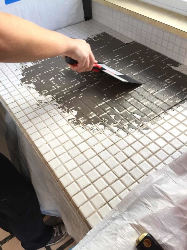 a person using a tile grouter on a tiled counter top in a kitchen